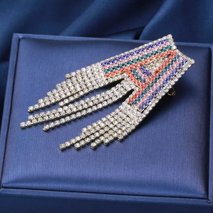 Macro shot of letter A brooch with colorful rhinestones and long silver tassels on blue box