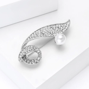 Detail view of silver leaf brooch with sparkling crystals and a large white pearl