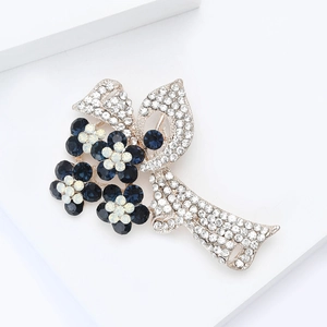 Élégante broche ruban floral avec cristaux bleus et strass blancs sur support blanc