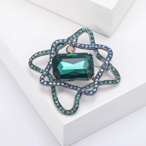 Macro view of emerald green crystal brooch with star-shaped geometric black nickel frame