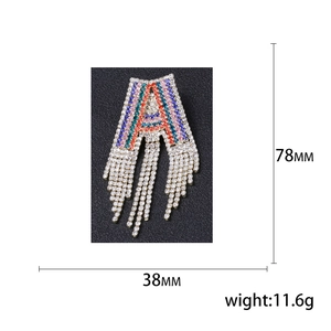Sparkling crystal letter A brooch with long tassel fringe on black leather background
