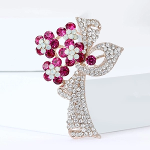 Détail d'une broche fleur dorée avec strass roses et transparents sur fond blanc