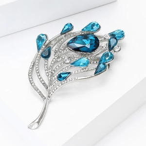 Détail d'une élégante broche plume avec pierres bleues et incrustations de zircons