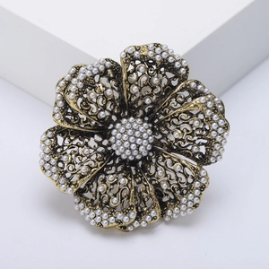 Vintage hollow flower brooch with pearl embellishments and antique metal finish on white stand