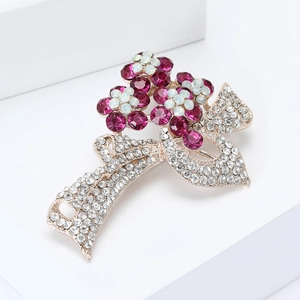 Vue détaillée de la broche florale en strass avec monture dorée sur support blanc