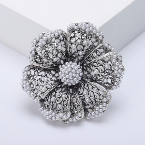 Detailed macro of vintage silver hollow flower brooch with white pearls for women