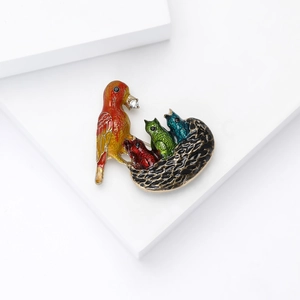 Macro detail of the creative mother bird and chicks nest brooch with colorful enamel finish