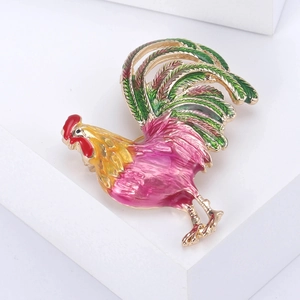 Détail d'une broche en forme de coq coloré avec finition émail et placage en or chic