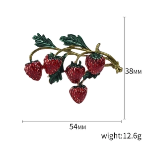 Broche fraise rouge dessin animé avec feuilles vertes et tiges dorées sur fond blanc