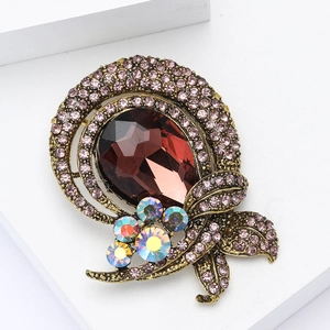 Detail of vintage glass brooch with red gemstone and purple rhinestones on gold base