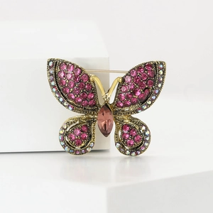 Detailed close-up of a vintage butterfly brooch with pink rhinestones on white stones