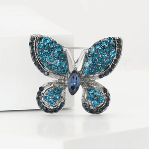 Detailed view of silver butterfly brooch with blue rhinestones and navette center stone