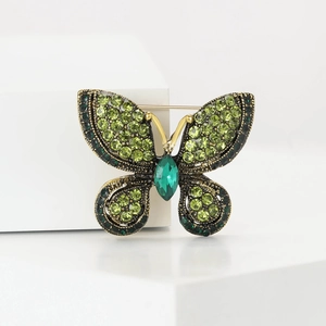 Detailed macro view of green crystal butterfly brooch with emerald accents and vintage metal