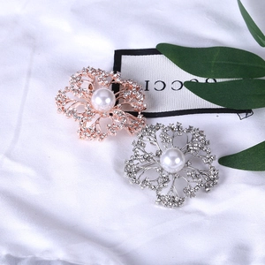 Detailed view of floral brooches with shimmering crystals and white pearls on silk