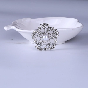 Detailed view of elegant floral brooch with pearl center and pavé rhinestones in silver