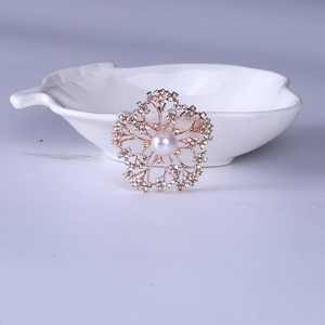 Detailed view of rose gold flower brooch with white pearl and sparkling crystals