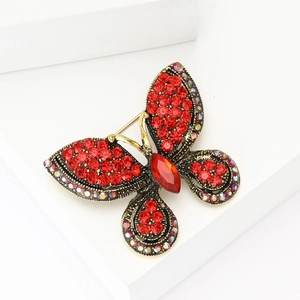 Vintage gold butterfly brooch with red rhinestones on a white geometric block pedestal
