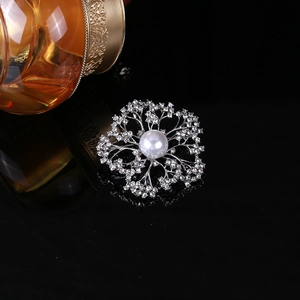 Detail of vintage flower brooch with white pearl and crystals on reflective black surface