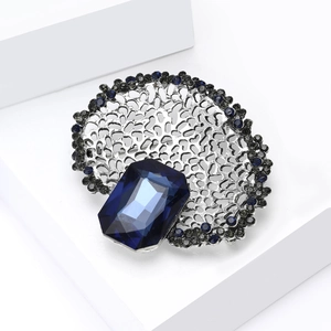 Macro shot of retro silver hollow brooch with large deep blue crystal and pavé rhinestones