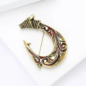 Vintage gold alloy fishhook brooch with red enamel and intricate scroll patterns