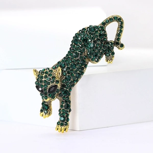 Close-up of golden leopard brooch featuring green rhinestones and intricate craftsmanship