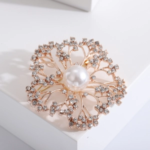 Elegant floral rhinestone brooch with a central pearl on a white geometric block