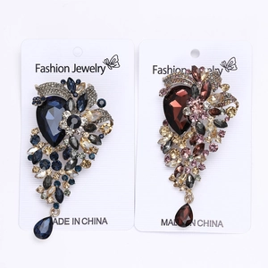 Detail of luxury crystal drop brooches in blue and burgundy with vintage silver plating
