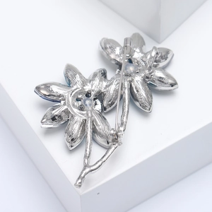 Detailed view of silver floral brooch featuring dual flower design and secure pin fastener