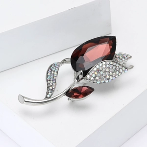 Elegant floral brooch with burgundy faceted gemstone and crystals on a silver setting