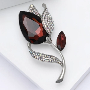 Detail of tulip brooch with deep red gemstone and sparkling rhinestones on silver base