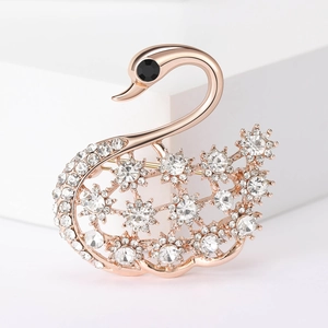 Broche cygne élégante en or rose avec cristaux étincelants sur socle blanc géométrique