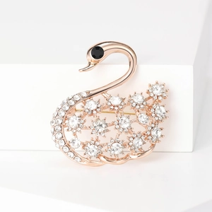 Détail d'une broche cygne or rose avec des grappes d'étoiles en cristal et œil de gemme noire