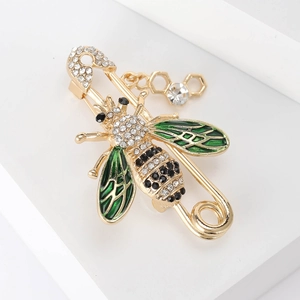 Détail macro d'une broche abeille dorée avec émail vert et pendentif alvéole en cristal brillant