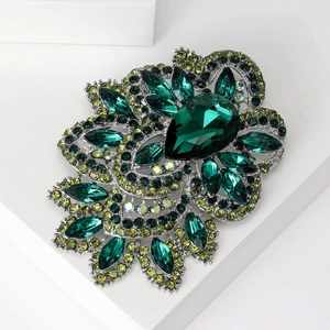 Detailed macro view of large green crystal brooch with silver metal floral base