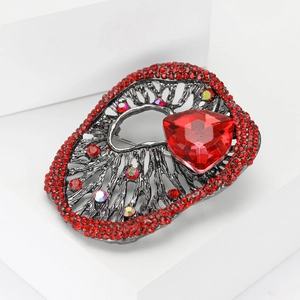 Detail of vintage gunmetal brooch with red triangular stone and crystals on stone background