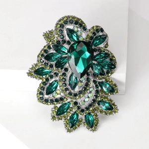 Macro detail of luxury baroque crystal brooch with emerald green teardrop stones