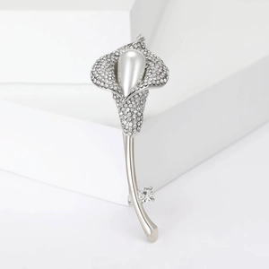 Détail d'une élégante broche calla avec cristaux blancs et grande perle en poire