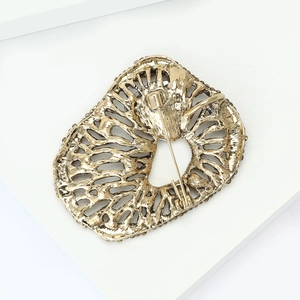 Macro view of vintage gold alloy brooch back with hollow texture and safety pin fastener