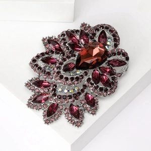 Macro view of crystal flower brooch with deep red teardrop stone and purple petals