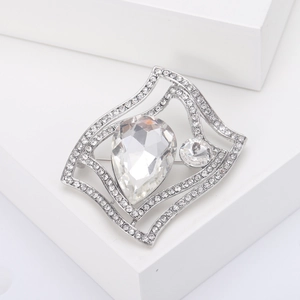 Macro shot of silver geometric brooch with sparkling clear crystals on white pedestal