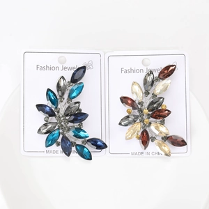 Detailed close-up of leaf-shaped brooches with blue and brown crystal marquise settings