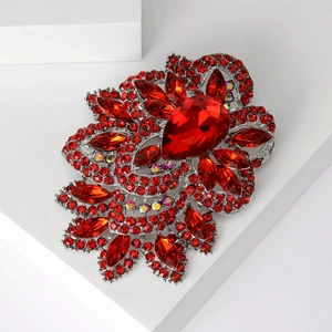 Detailed macro shot of vintage brooch featuring red pear-shaped crystals and silver plating
