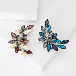 Elegant marquise crystal leaf brooches in warm and cool tones on white geometric blocks