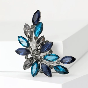 Detail of flower brooch with marquise-cut blue and grey crystals on white background