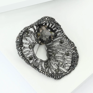 Detailed macro view of a heart-shaped grey crystal set in gunmetal filigree brooch