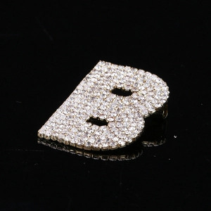 Vue macro détaillée de la broche dorée lettre B avec des strass étincelants sur fond noir