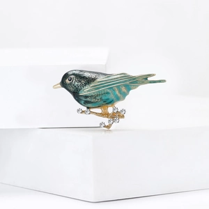 Enamel green bird brooch with golden outlines and sparkling rhinestones on branches