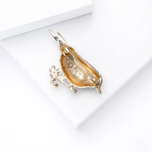 Detailed back view of a gold-plated bird brooch showing safety pin and star texture