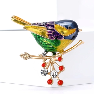 Macro d'une broche oiseau en émail coloré avec perles rouges et strass sur branche dorée