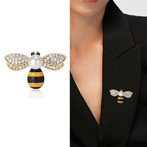 Elegante spilla a forma di ape dorata con perle e cristalli su un bavero di giacca nera